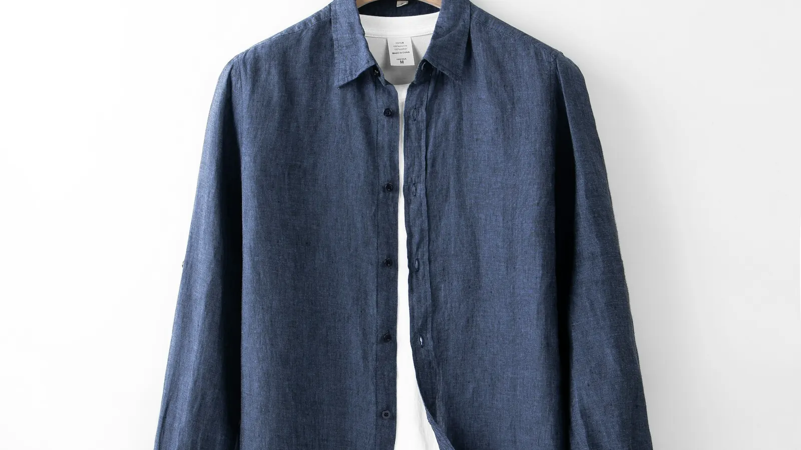 Close view of the collar, buttons and woven fabric of a blue linen shirt