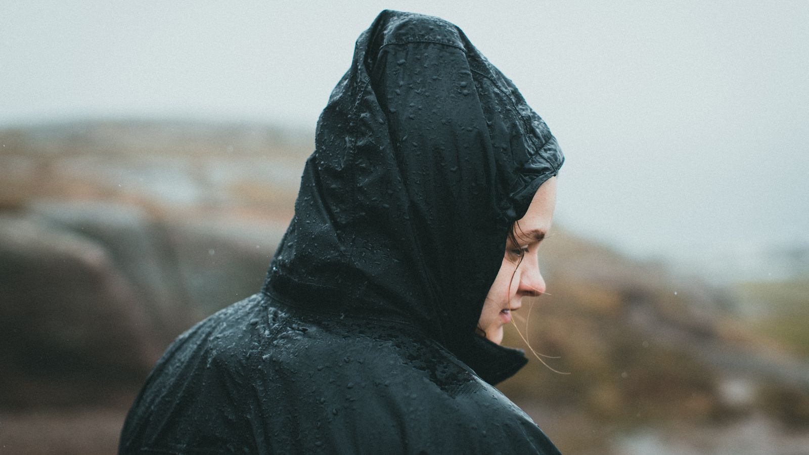 Raindrops beading on the hood and shoulder of a black waterproof jacket outdoors.