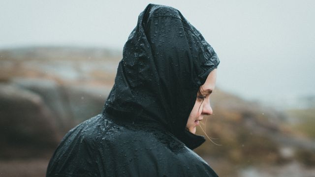 Raindrops beading on the hood and shoulder of a black waterproof jacket outdoors.